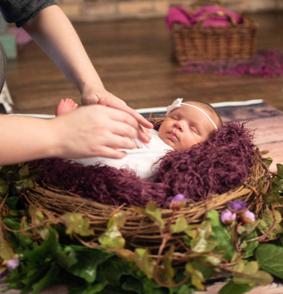 A woman is holding a baby in a basket.