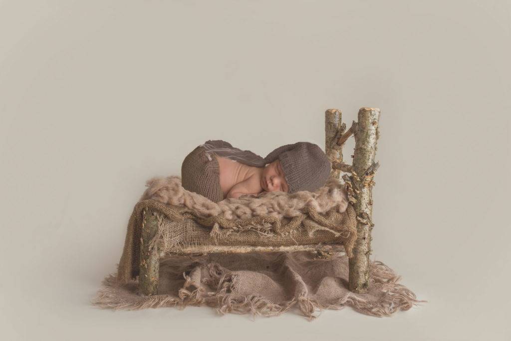 A newborn baby sleeping in a wooden chair.