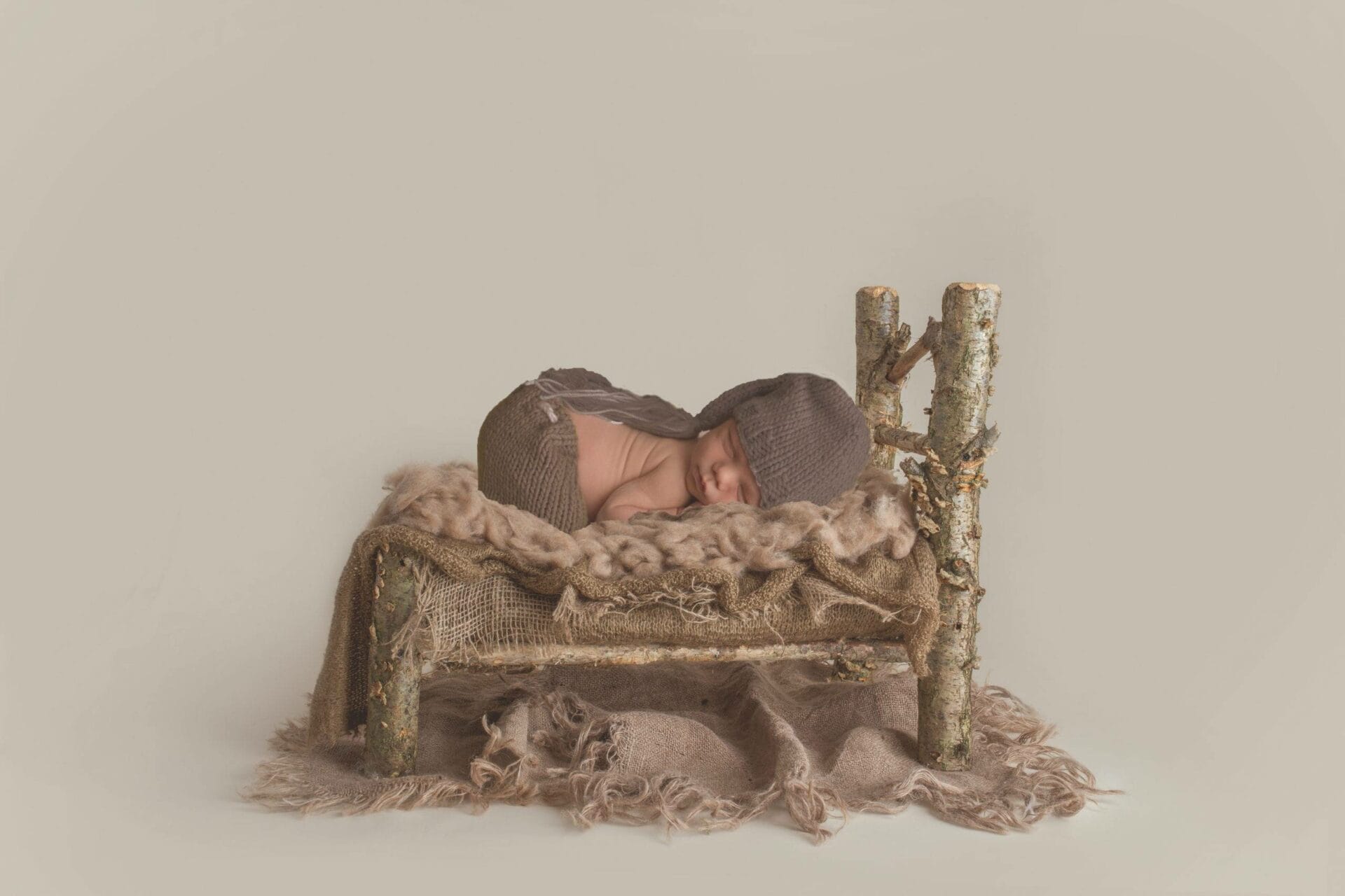 A newborn baby sleeping in a wooden chair.