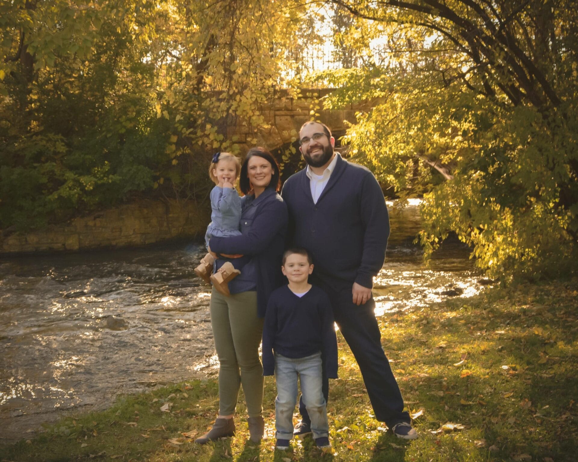 A family is posing in front of a river.