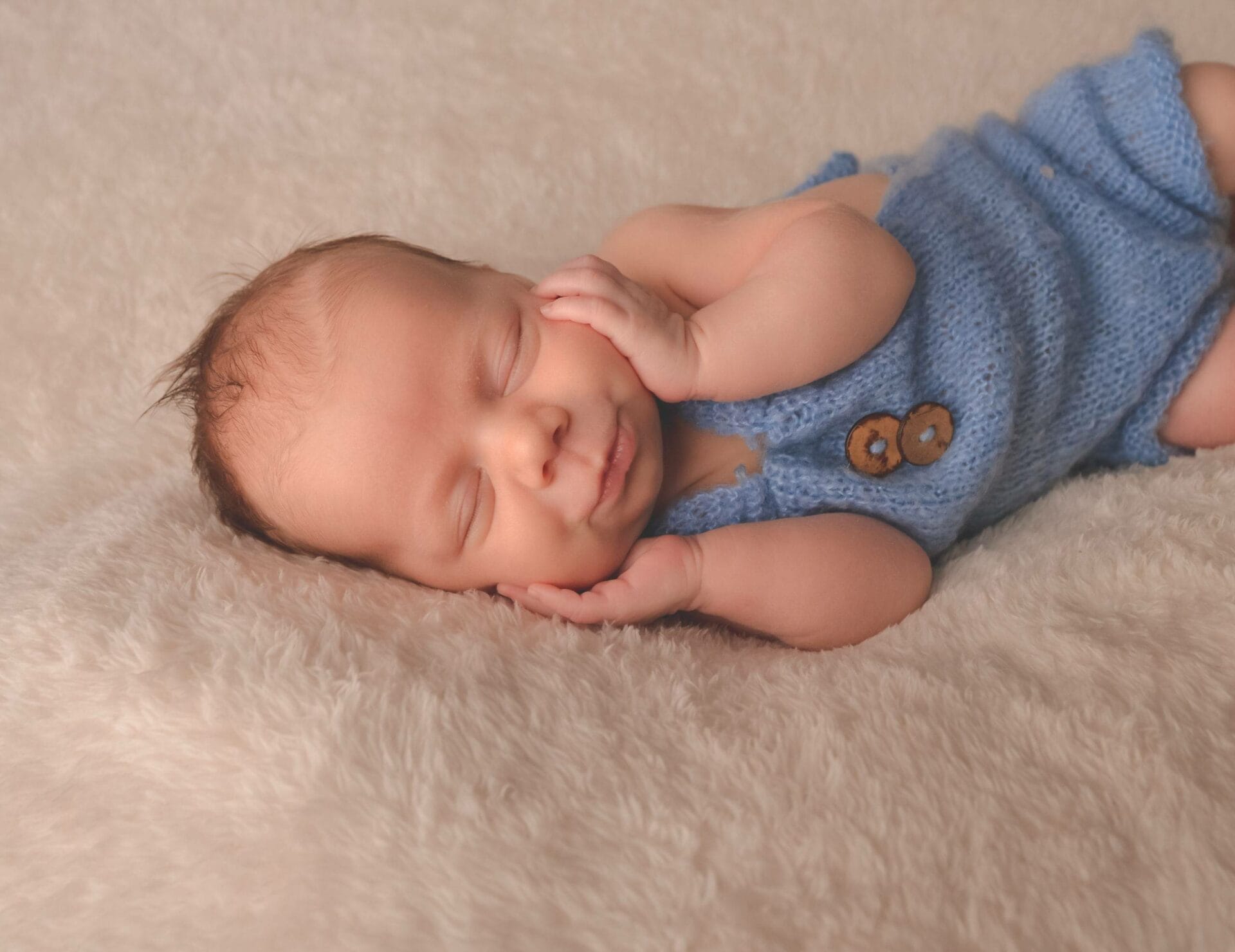 A baby sleeping on a white blanket.