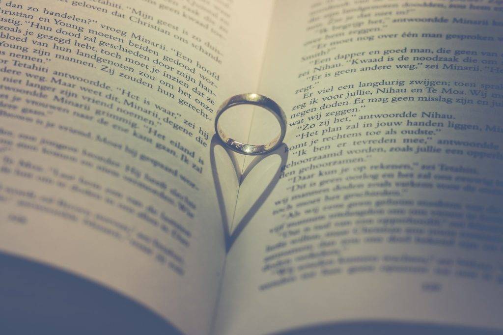 A wedding ring in the shape of a heart on an open book.