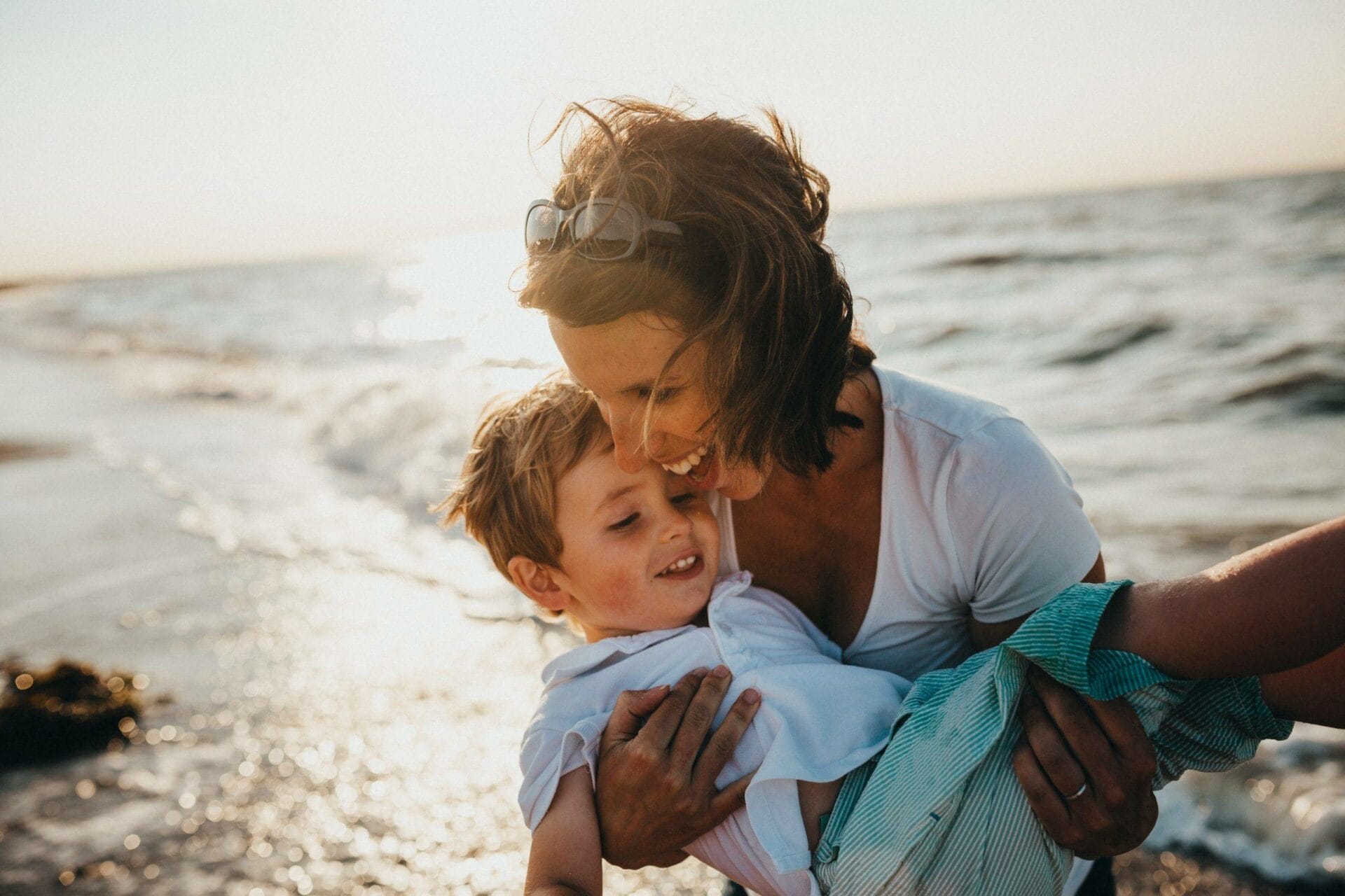 A mother holding her son on the beach.