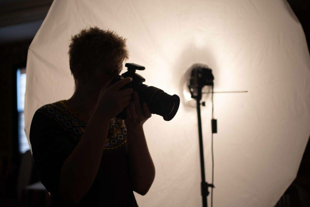 A woman taking a picture with a camera in front of a light.