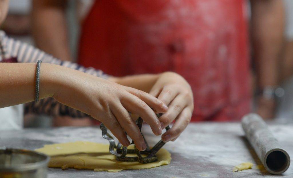 A girl is kneading dough on a table.