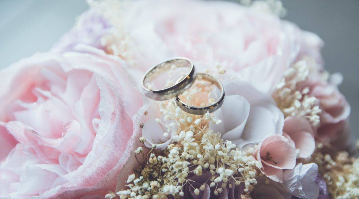 Two wedding rings on a bouquet of pink flowers.