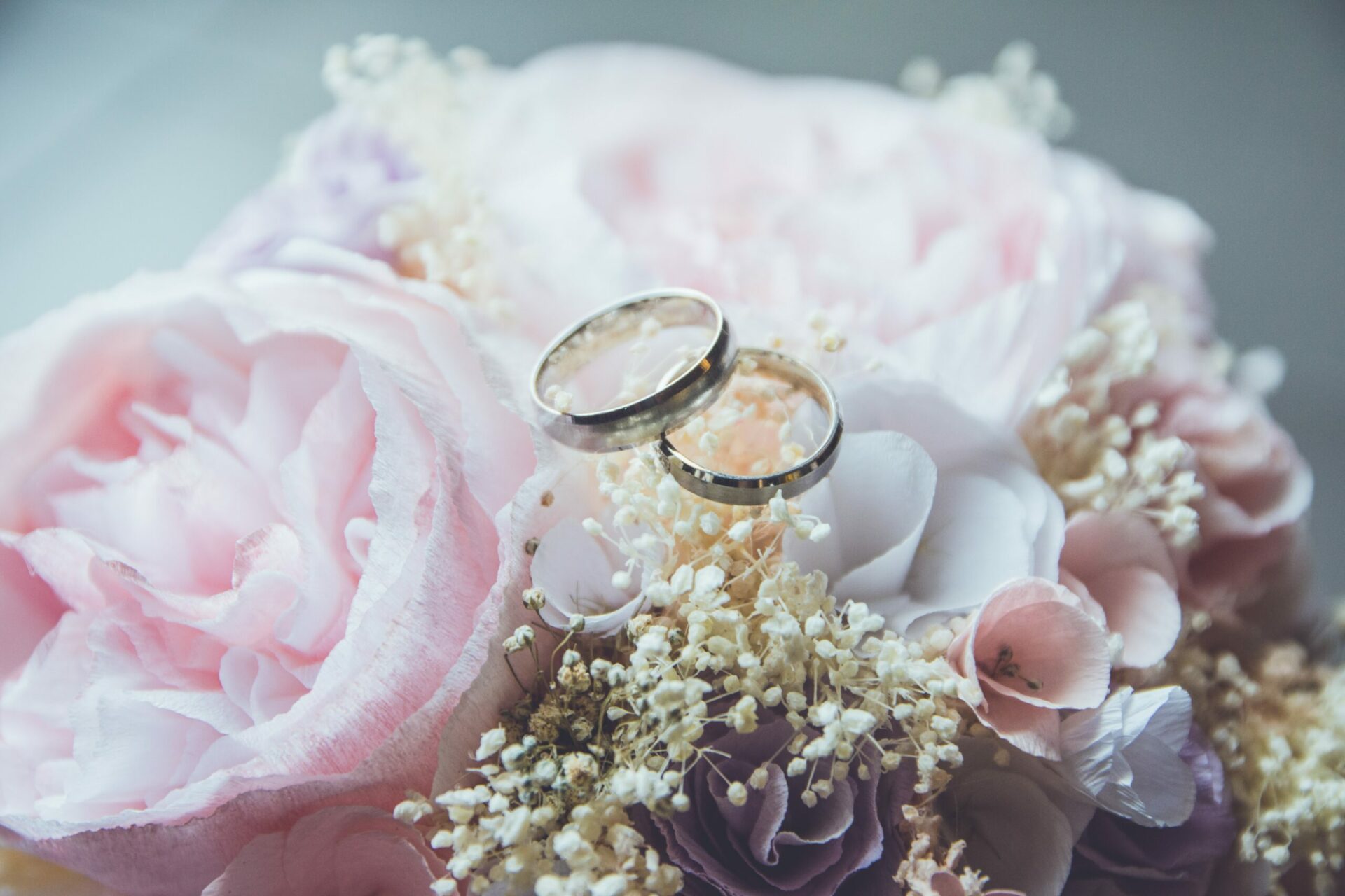 Two wedding rings on a bouquet of pink flowers.