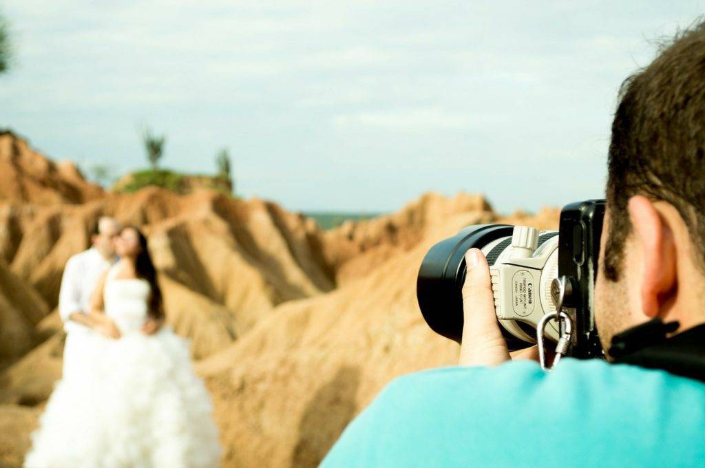 A wedding photographer taking a picture of a bride and groom.