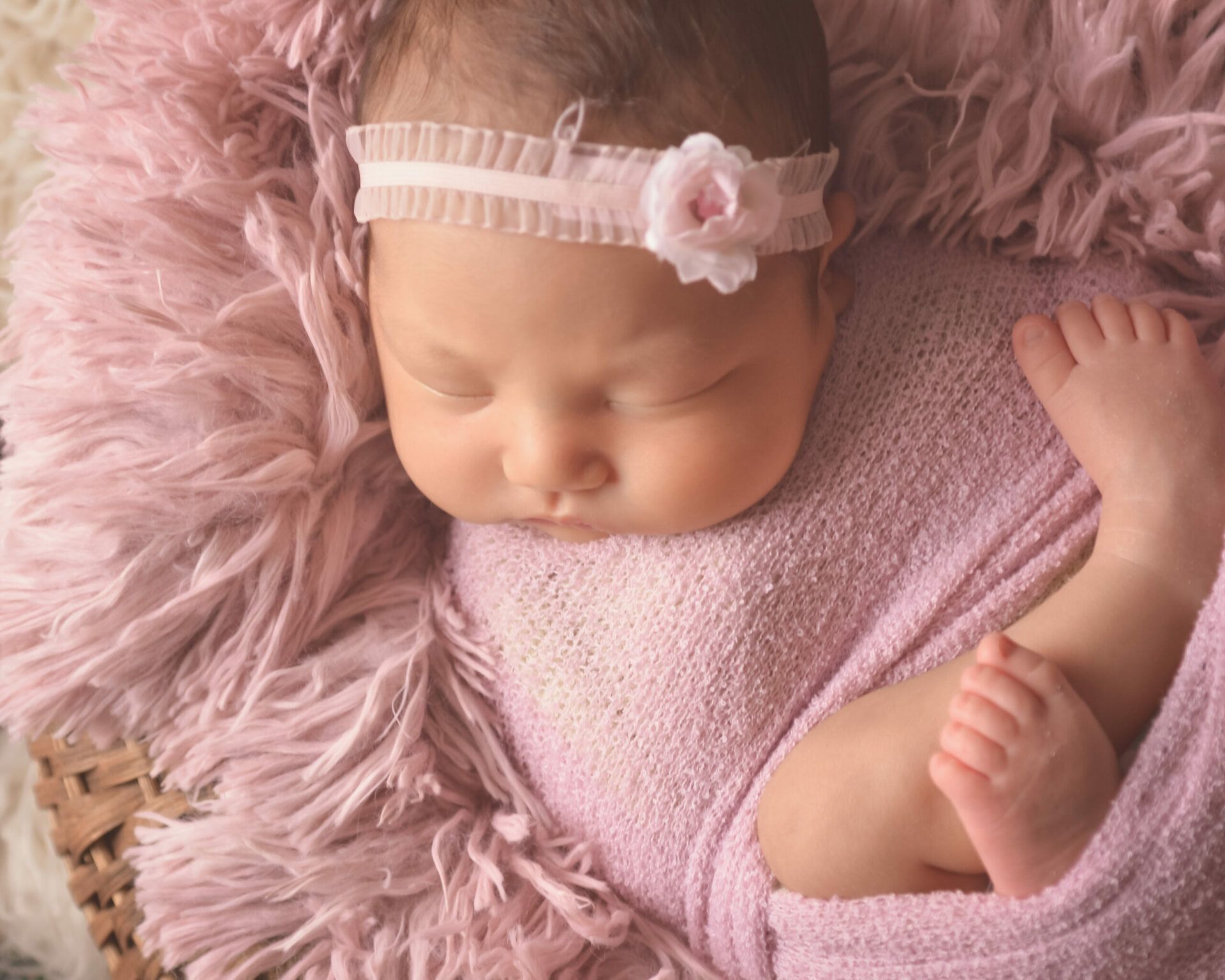 A newborn girl sleeping in a pink blanket.