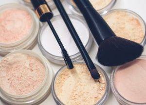 A variety of makeup brushes and powders on a white surface.