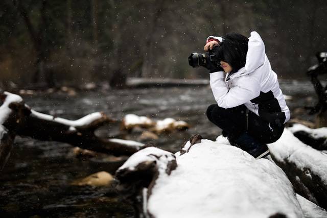 A person is taking a picture of a river in the snow.