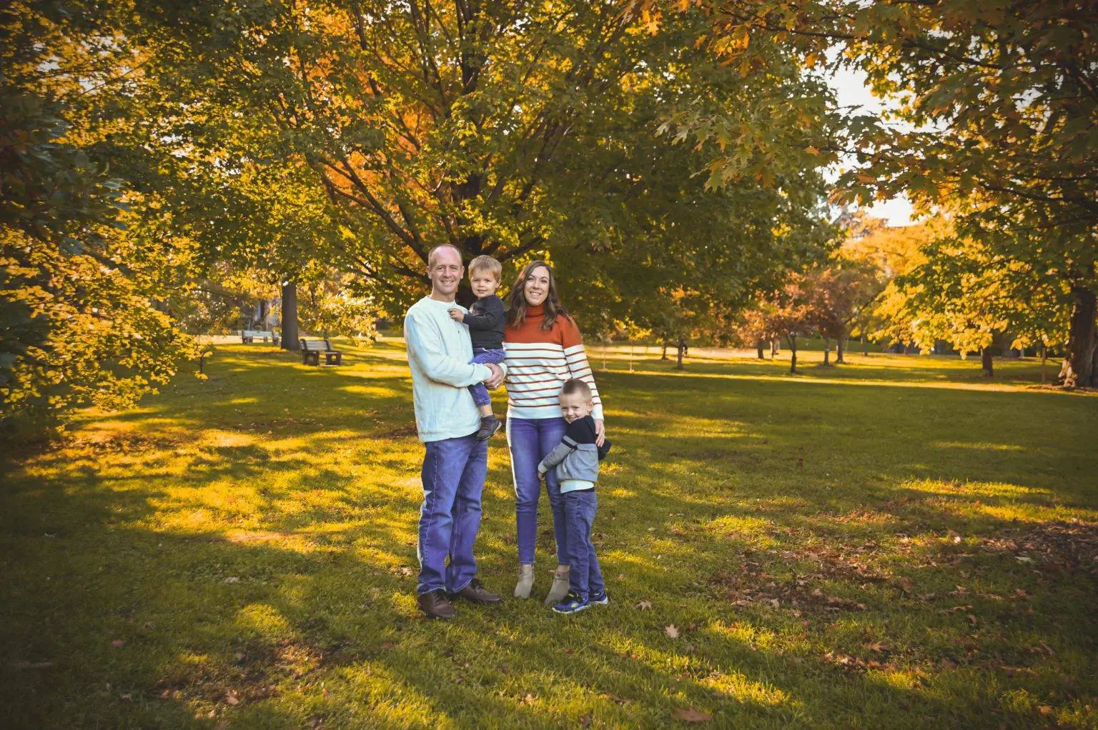 A family is posing for a photo in a park for their maternity photography session.