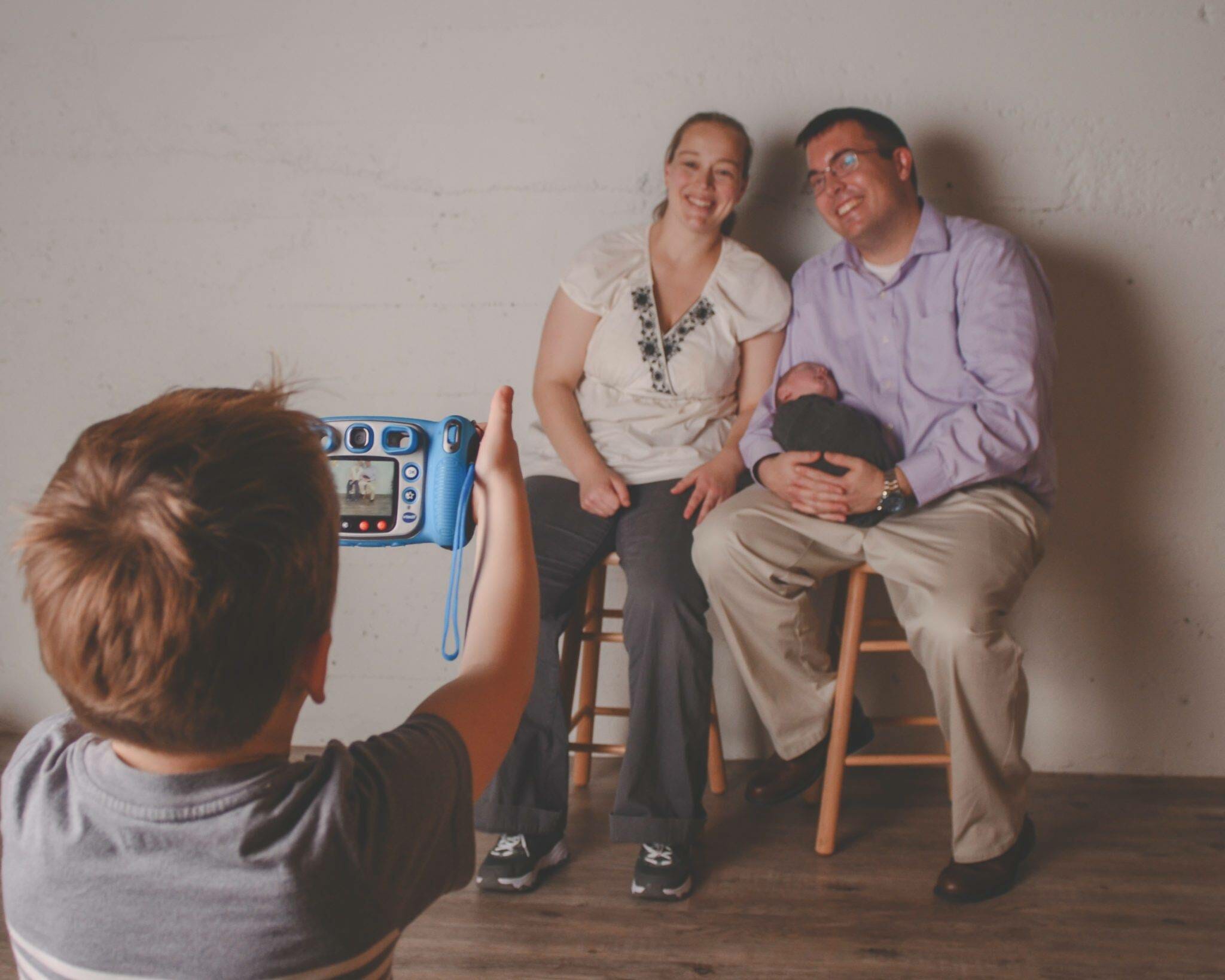A man and a woman taking a picture of their son.