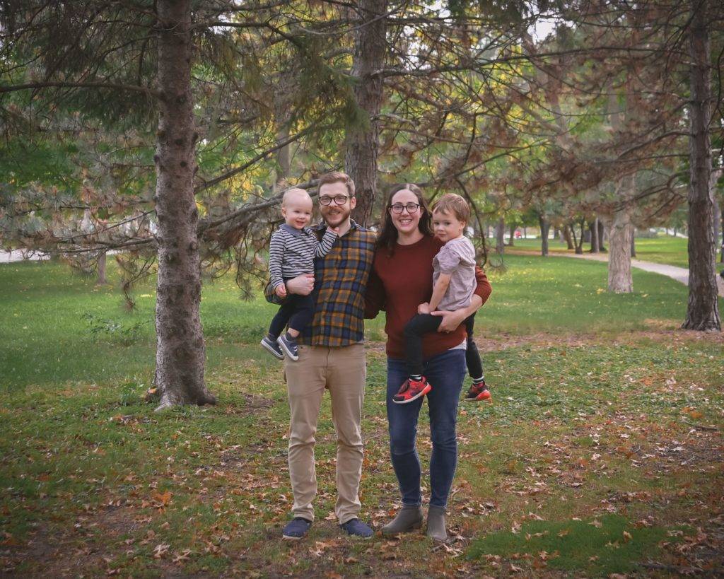 A family poses in front of a tree in a park.