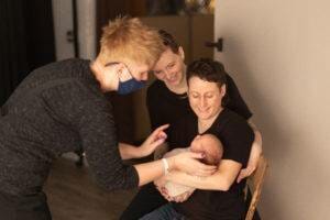 A group of women are holding a baby in front of Minnesota photographer Giliane Mansfeldt's camera.