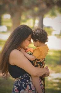 A woman holding a baby in her arms in a park.