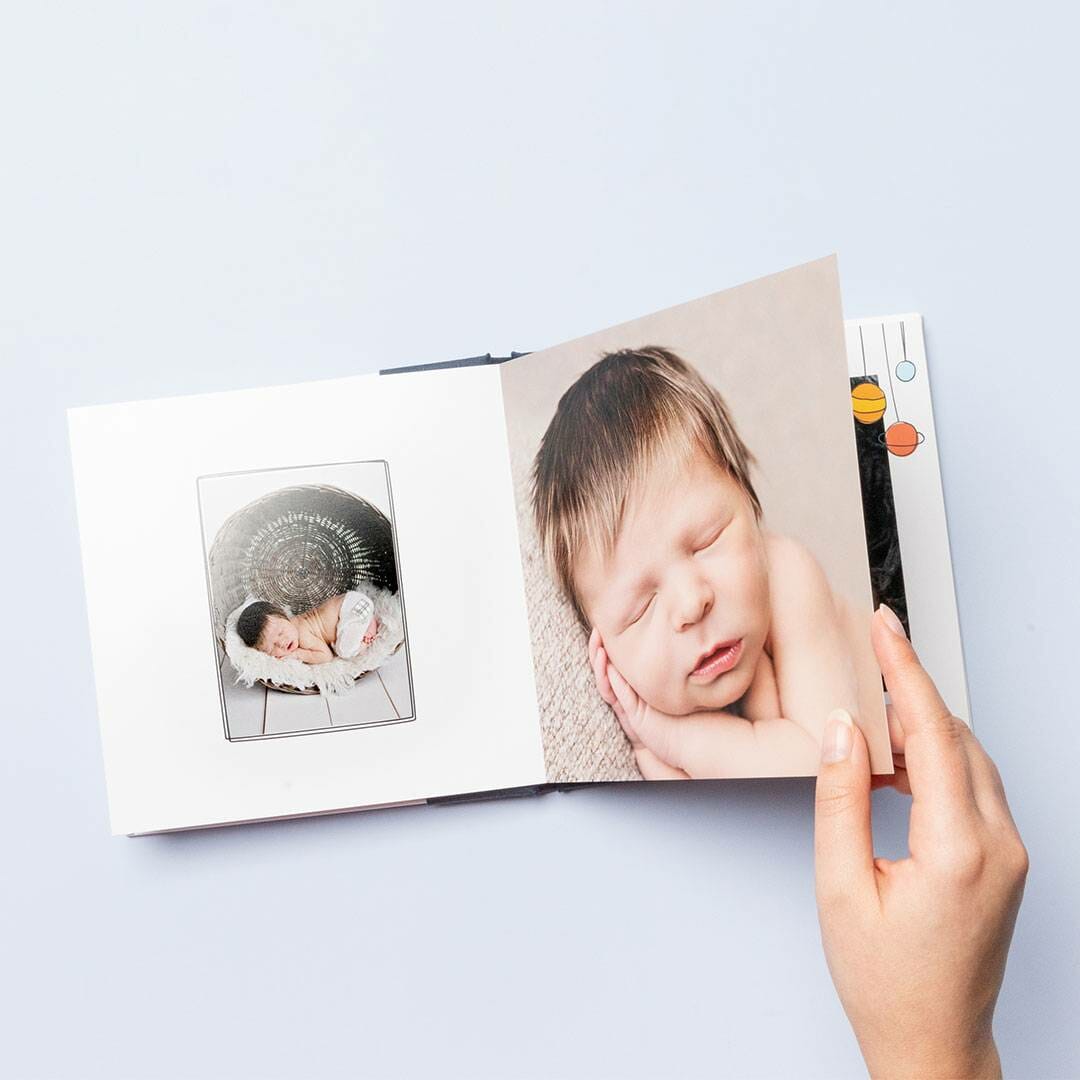 A person holding an open book with a photo of a baby.