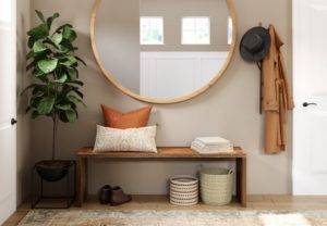 An entryway with a bench and a round mirror.