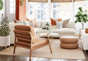 A living room with white furniture and orange accents.