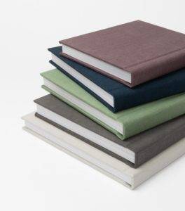 Four books stacked on top of each other on a white surface.