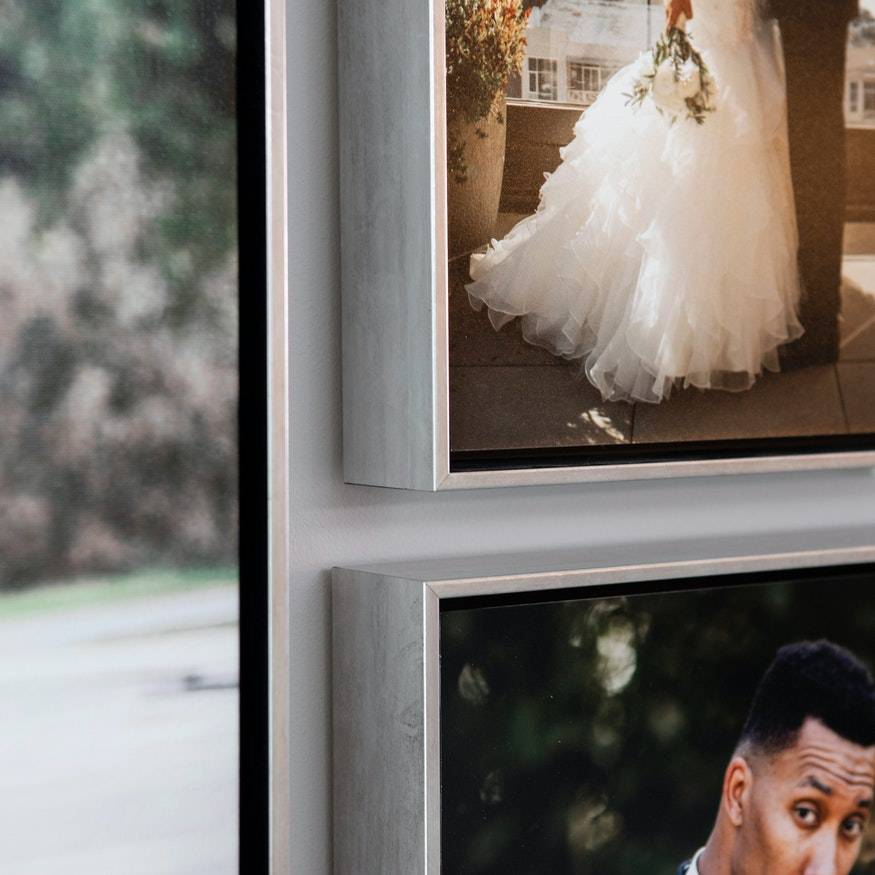 A bride and groom's wedding photos are framed on a wall.