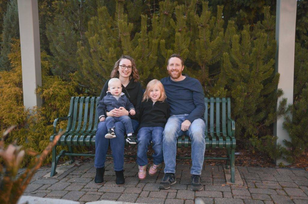 A family sits on a bench in a park.