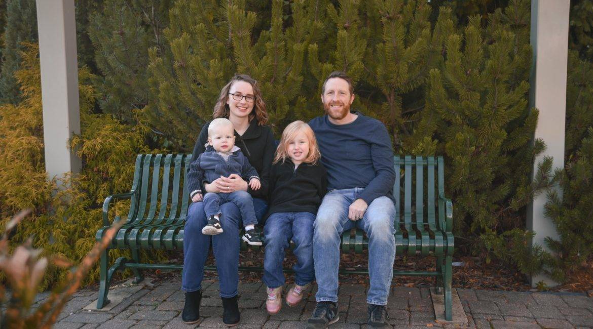 A family sits on a bench in a park.