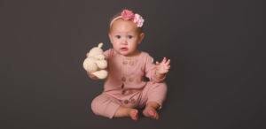 A baby cherishing a teddy bear on a gray background in adorable children photography.