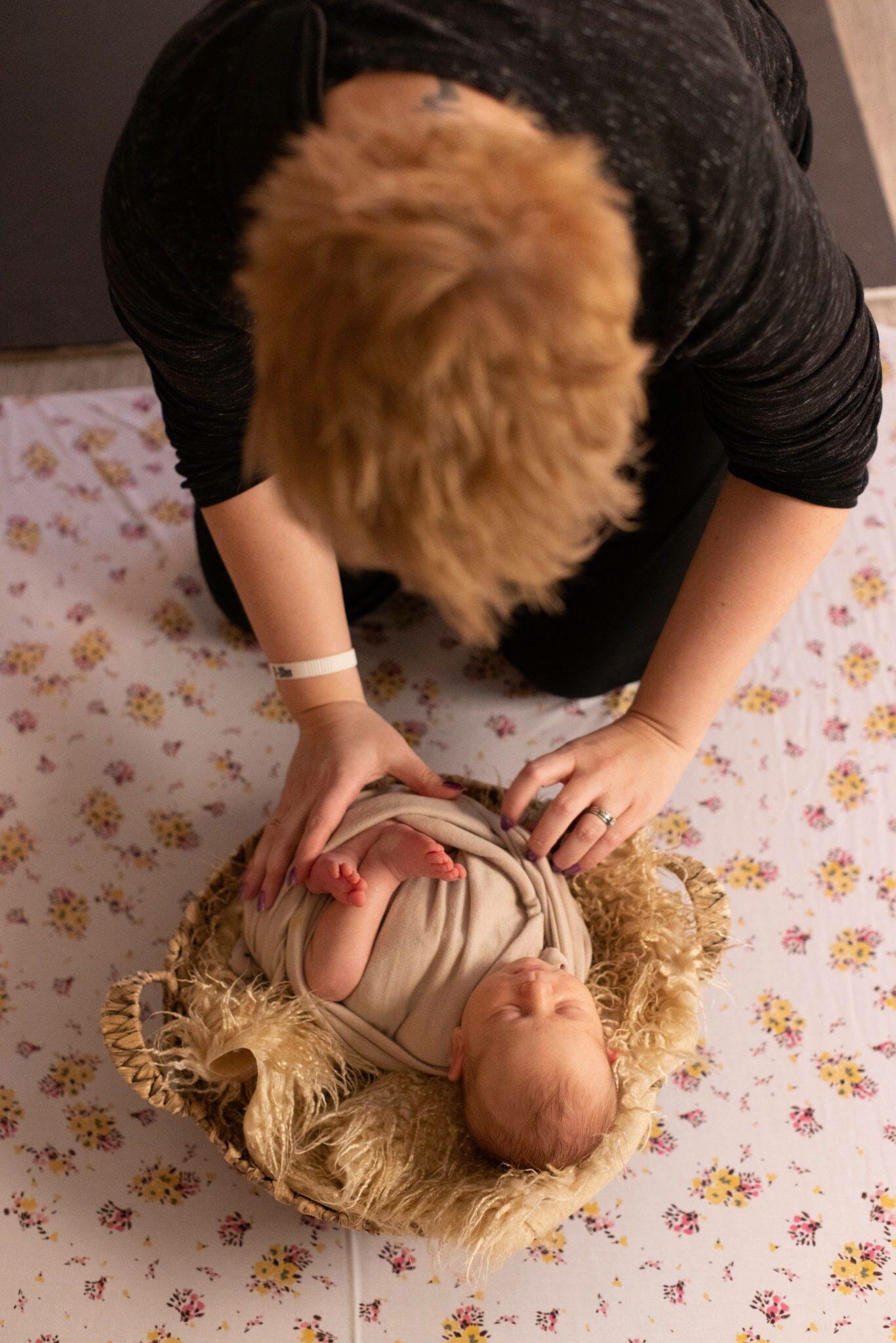 A woman is holding a baby in a basket.