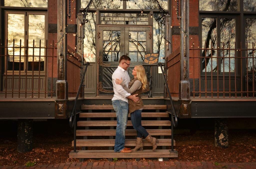 An engaged couple standing on the steps of a building.