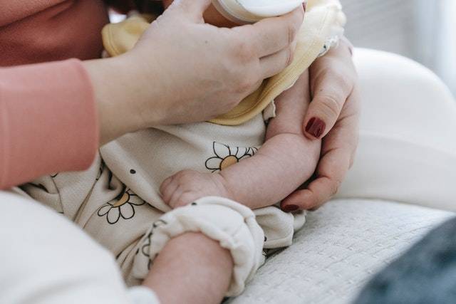 A woman feeding a baby with a bottle.