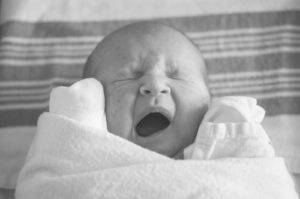 A black and white photo of a baby yawning.