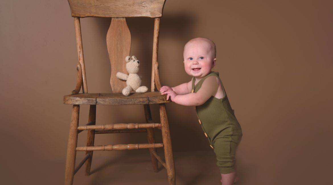 6 month photos, baby standing by chair