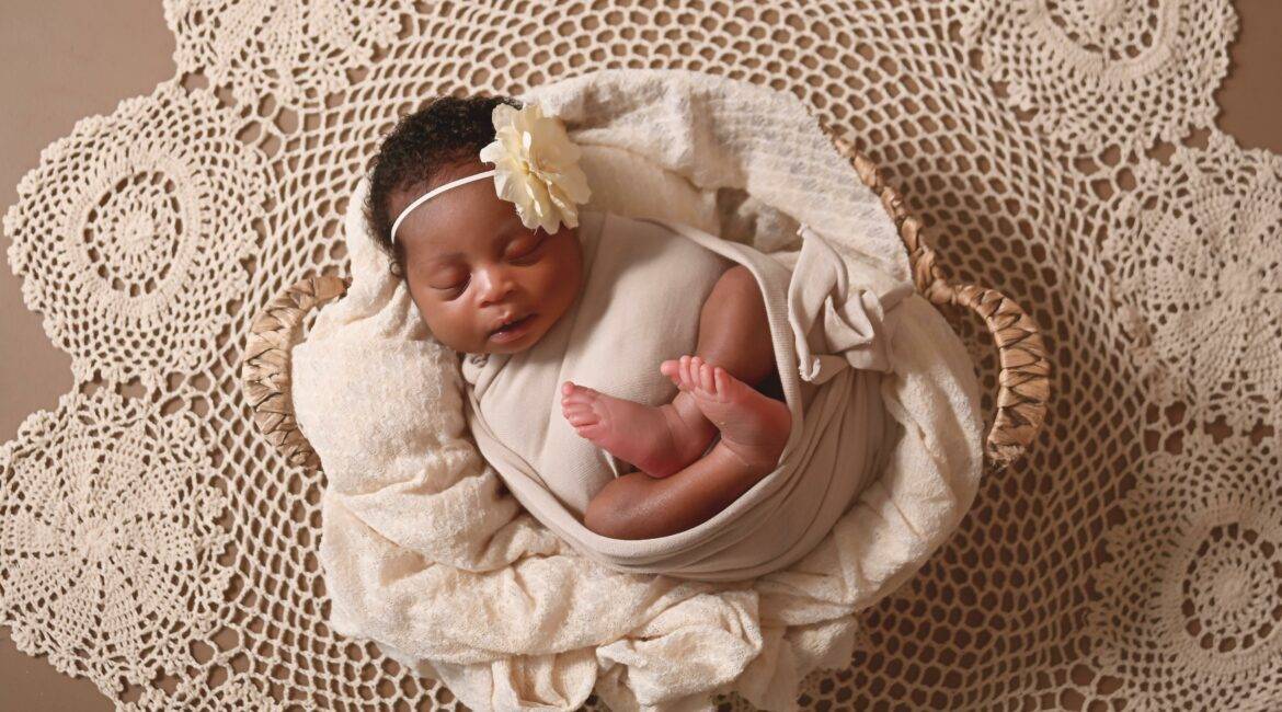 A newborn baby girl in a basket on a doily.