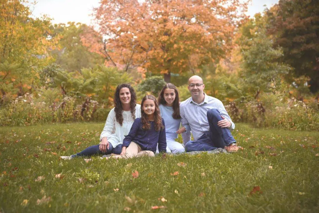 A family sits on the grass in an autumn park.