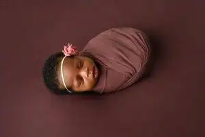 A newborn baby sleeping on a brown background.