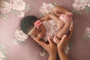 A baby girl is lying on her mother's hands.