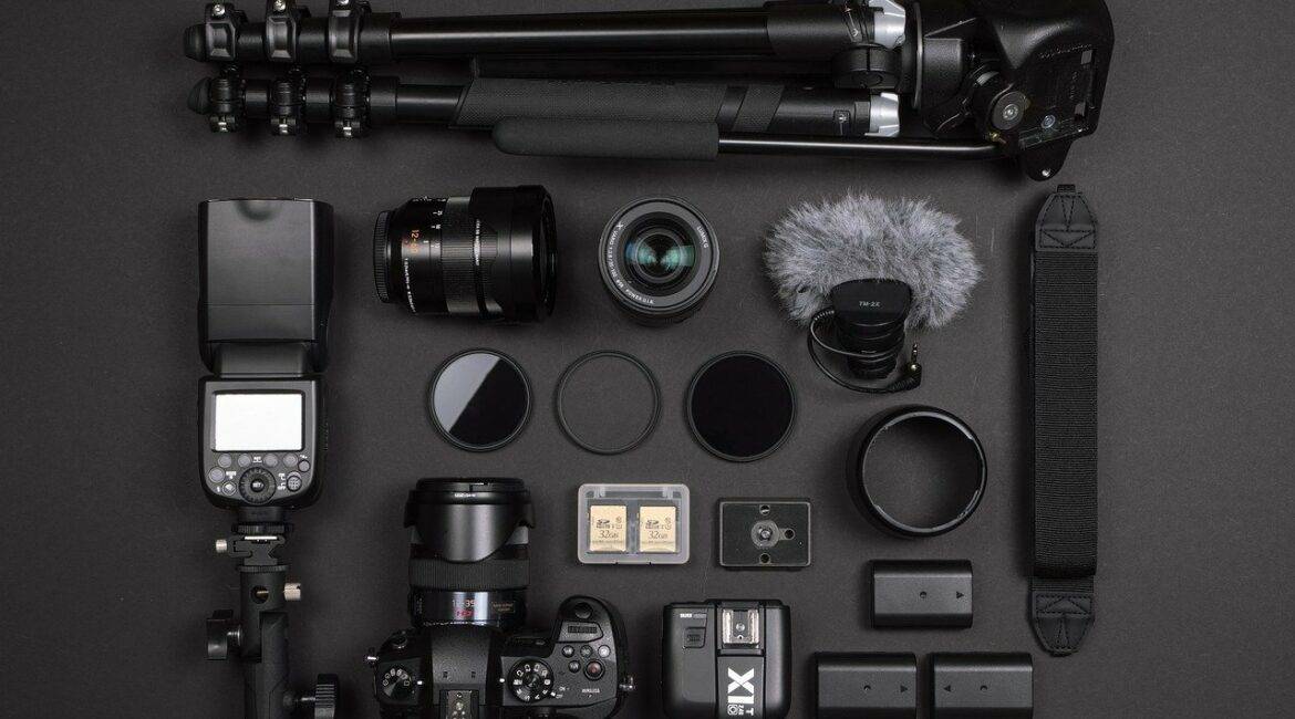 A camera, lens, and other equipment laid out on a black surface.