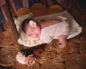A baby girl is sleeping in a basket on a rug.