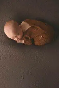 A baby sleeping on a brown blanket.