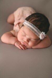 A baby girl sleeping on a gray background.