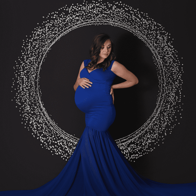 A pregnant woman in a blue dress posing in front of a mirror.