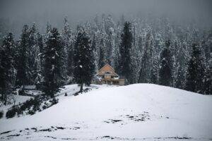 A house is sitting on top of a snow covered hill.
