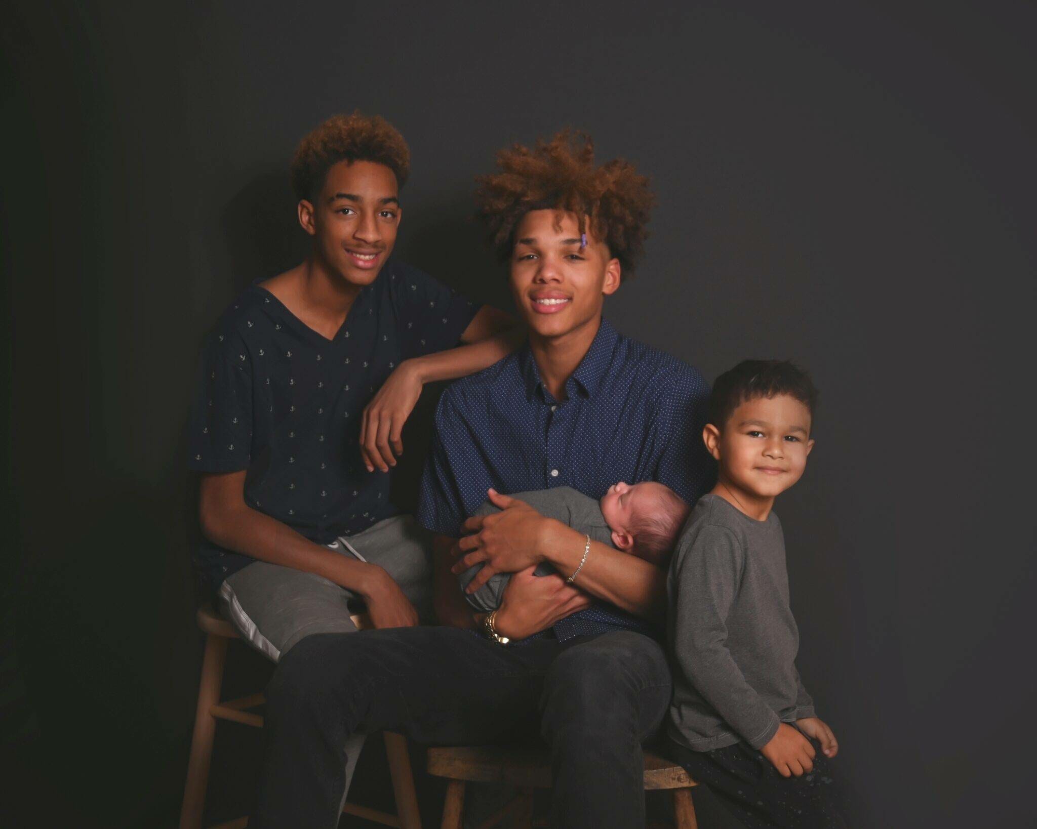 A family posing for a photo in front of a black background.