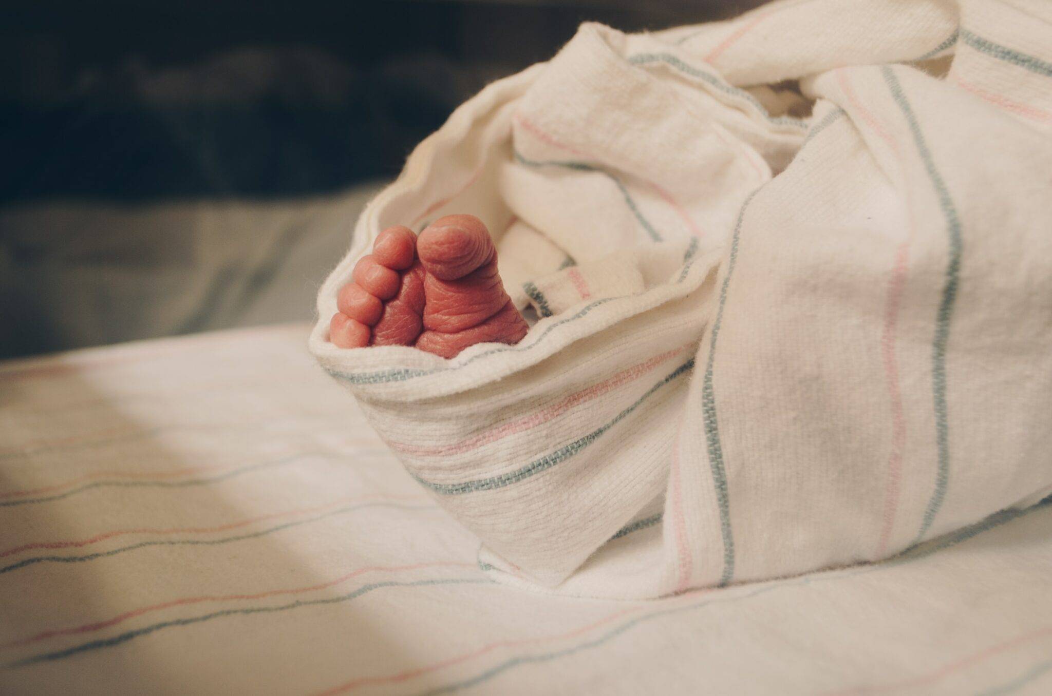 A baby's foot wrapped in a blanket on a bed.