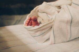 A baby's foot wrapped in a blanket on a bed.