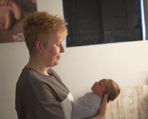 A woman holding a newborn in a room captured through newborn photography in Saint Paul, Minnesota.