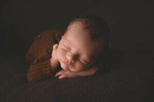 A newborn peacefully sleeping on a couch for family photography in Saint Paul, Minnesota.