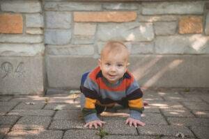 A baby crawling on a brick surface captured in baby photography.