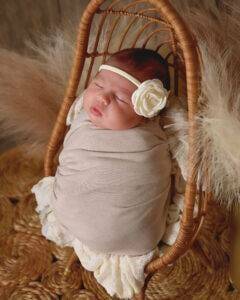 A baby girl is sleeping in a wicker basket.